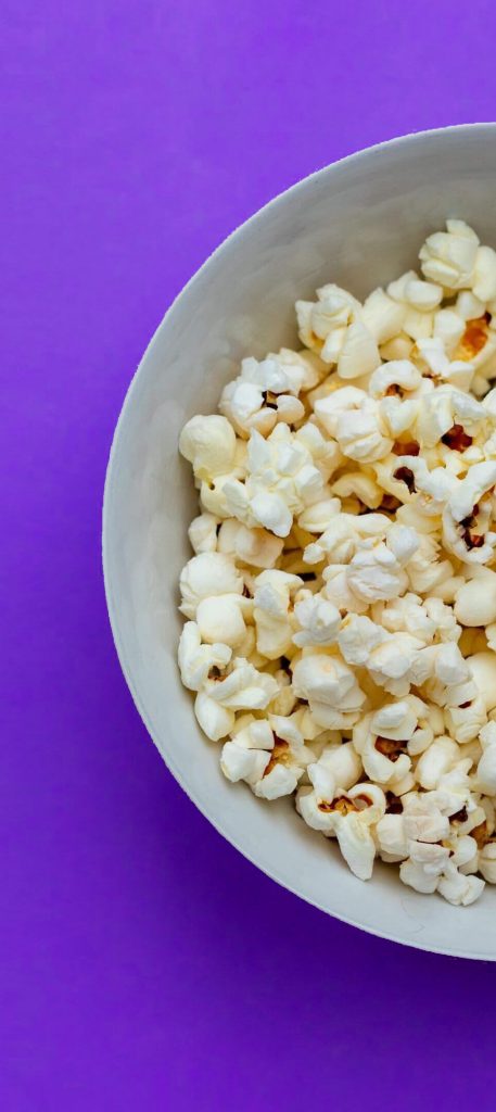 bowl with popcorn on purple background